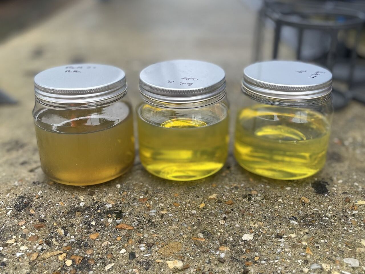 Three fuel samples drawn from the top, middle and bottom of the same storage tank, one visibly hazier than the others